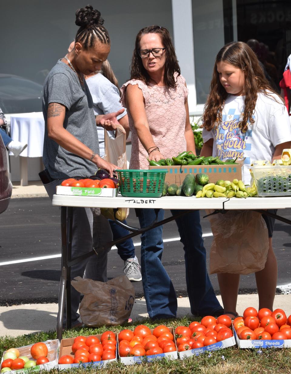 Outside of David’s House in Richmond, Brandie Doan, center, explains how certain vegetables can be used in meal preparation. The new ministry of the Tri-County Good Samaritans conference will offer fresh produce in an impoverished food-desert area of the city.