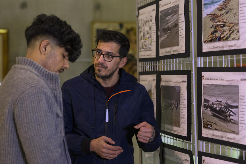 Mojtaba Rezapour Moghaddam, 47, from Mashad, Iran, right, and Haroon Mohammadi, 24, from Herat, Afghanistan, who survived the shipwreck of a migrant boat that capsized in the early morning of Sunday, Feb. 26, 2023, at a short distance from the shore in Steccato di Cutro, near Crotone in the Italian southern tip, killing at least 94 people, visit a photo exhibition on the disaster set up in Crotone, Saturday, Feb. 24, 2024. Survivors and family members of the victims are converging in the area for a commemoration on Monday, Feb. 26, 2024, on the first anniversary of the disaster. (AP Photo/Valeria Ferraro)