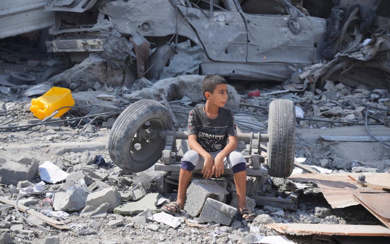 A Palestinian boy sits on the rubble of his building destroyed in an Israeli airstrike in Nuseirat camp in the central Gaza Strip on Monday, Oct. 16, 2023.