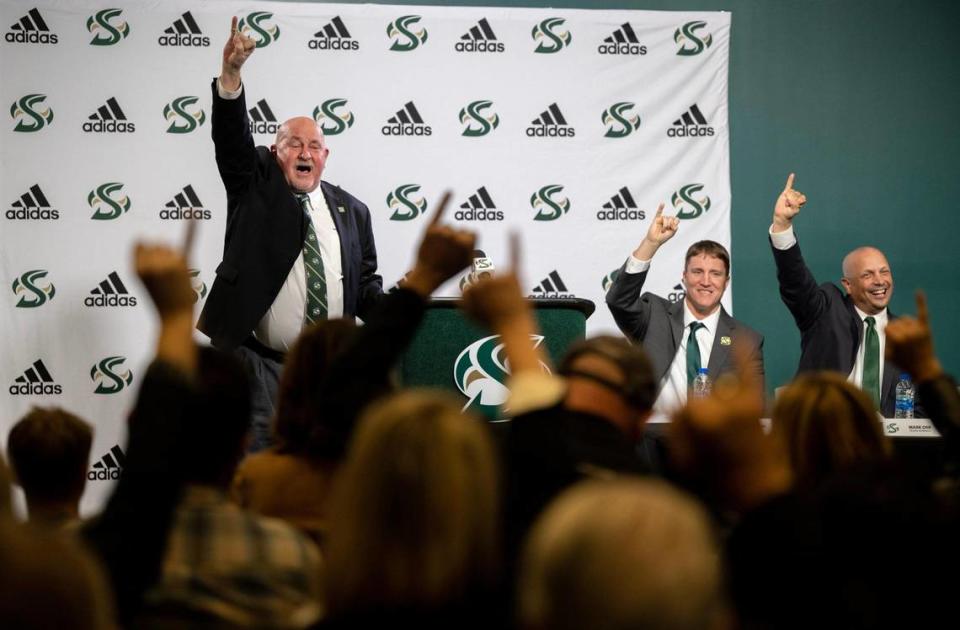 Sacramento State President Dr. Robert S. Nelson, left, congratulates Andy Thompson, the school’s new State football coach, right, and athletics director Mark Orr, far right, with a stingers-up gesture during press conference introducing the coach at the Sacramento State in 2022.