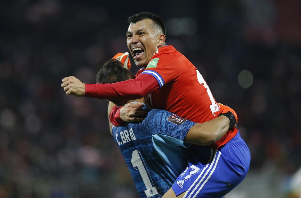 Chile's Gary Medel, top, celebrates with his teammates Claudio Bravo after teammate Benjamin Brereton scored his side's third goal against Venezuela during a qualifying soccer match for the FIFA World Cup Qatar 2022 at San Carlos de Apoquindo stadium in Santiago, Chile, Thursday, Oct. 14, 2021. (Claudio Reyes/Pool via AP)