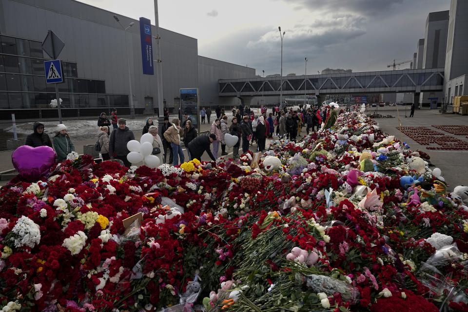 People lay flowers and toys at a makeshift memorial in front of the Crocus City Hall on the western outskirts of Moscow, Russia, Tuesday, March 26, 2024. Russia is still reeling from the attack Friday in which gunmen killed 139 people in the Crocus City Hall, a concert venue on the outskirts of Moscow. Health officials said about 90 people remain hospitalized, with 22 of them, including two children, in grave condition. (AP Photo/Alexander Zemlianichenko)