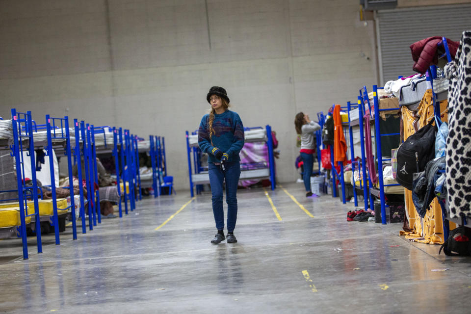 A migrant walks between rows of bunk beds at a government run shelter in Ciudad Juarez, Mexico, Sunday, Dec. 18, 2022. Texas border cities were preparing Sunday for a surge of as many as 5,000 new migrants a day across the U.S.-Mexico border as pandemic-era immigration restrictions expire this week, setting in motion plans for providing emergency housing, food and other essentials. (AP Photo/Andres Leighton)