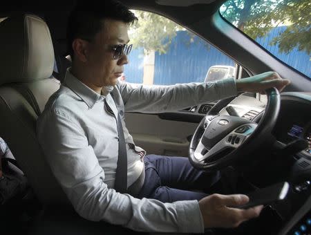 Chy Sila, CEO of CBM Corporation, holds his mobile phone while driving a car in Phnom Penh August 28, 2014. REUTERS/Samrang Pring