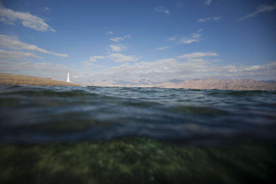 This Monday, Feb. 11, 2019 photo, shows a diver's view of the Red Sea with a marine observatory in the distance, in the Red Sea city of Eilat, southern Israel. As the outlook for coral reefs across our warming planet grows grimmer than ever, scientists have discovered a rare glimmer of hope: the corals of the northern Red Sea may survive, and even thrive, into the next century. The coral reefs at the northernmost tip of the Red Sea are exhibiting remarkable resistance to the rising water temperatures and acidification facing the region, according recent research conducted by the Interuniversity Institute for Marine Sciences. (AP Photo/Ariel Schalit)