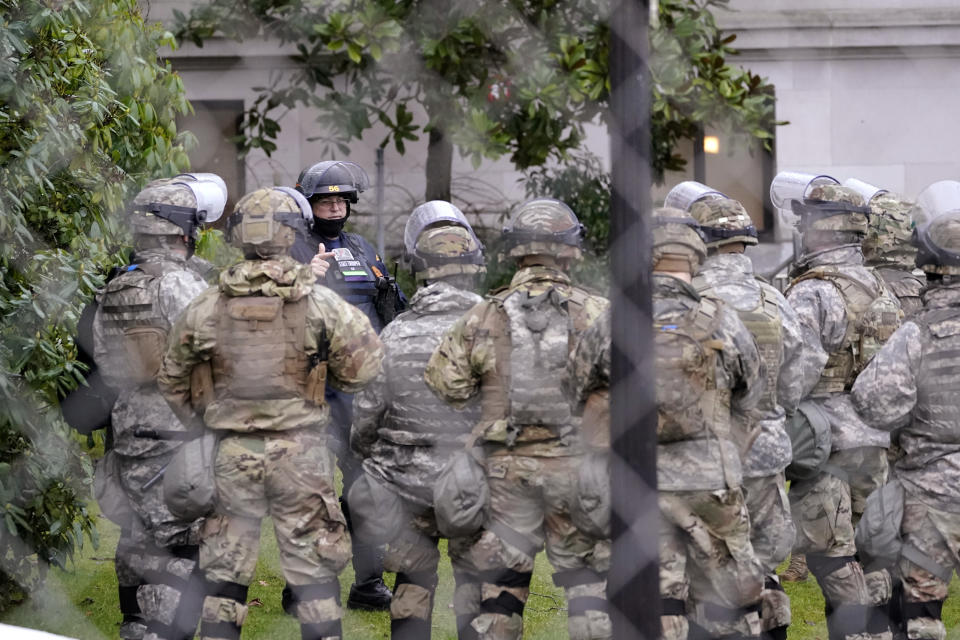A Washington State Patrol trooper talks with members of the Washington National Guard inside a fence surrounding the Capitol in anticipation of protests Monday, Jan. 11, 2021, in Olympia, Wash. State capitols across the country are under heightened security after the siege of the U.S. Capitol last week. (AP Photo/Ted S. Warren)