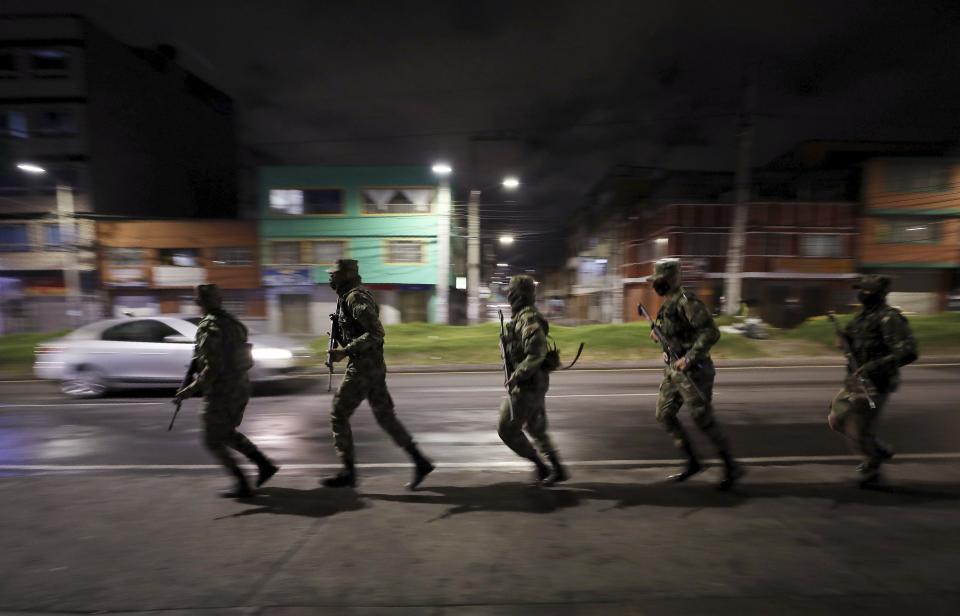 Soldiers run to a military truck to change checkpoint during an official continuous multi-day curfew in an effort to contain the spread of new coronavirus infections, in Bogota, Colombia, Friday, Jan. 22, 2021. Colombia's capital city is reimposing lockdown measures as COVID-19 infections rise around the country. (AP Photo/Fernando Vergara)