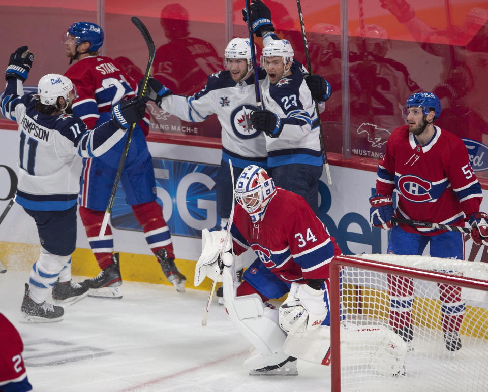 Winnipeg Jets center Trevor Lewis (23) celebrates his goal with teammates Jansen Harkins (12) and Nate Thompson (11) as Montreal Canadiens goaltender Jake Allen (34), Eric Staal (12) and Victor Mete (53) look on during the first period of an NHL hockey game, Thursday, April 8, 2021 in Montreal. (Ryan Remiorz/The Canadian Press via AP)