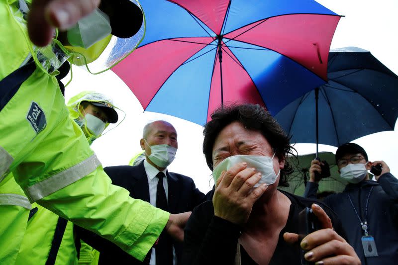 A woman mourns as the hearse carrying late Seoul Mayor Park Won-soon leaves Seoul City Hall Plaza after his funeral, in Seoul