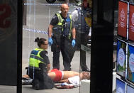 Police and medical staff surround a man as he lies on the footpath after a car hit pedestrians in central Melbourne, Australia, January 20, 2017. AAP/AAP Image/via REUTERS