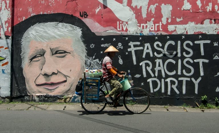 A man cycles past graffiti condemning US Republican presidential nominee Donald Trump, on a street in Surabaya, Indonesia's east Java on October 17, 2016