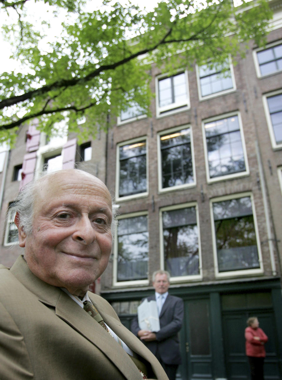 FILE - In this June 25, 2007 file photo Anne Frank's cousin Bernhard "Buddy" Elias, left, poses for a portrait as director of the Anne Frank Foundation Hans Westra, center background, hold some of the 25,000 letters, photographs and documents from the Frank family archive Elias permanently loaned to the Anne Frank House, in front of the Anne Frank House in Amsterdam, Netherlands. Two nonprofit organizations, The Anne Frank Fund, based in Basel, Switzerland and The Anne Frank Foundation, which manages the museum located in Amsterdam, are locked in a dispute over the Frank family archives, which have been kept in Amsterdam since 2007. Foundation spokeswoman Maatje Mostart said Wednesday May 8, 2013 of the fight “it's really sad this is happening." (AP Photo/Peter Dejong, File)