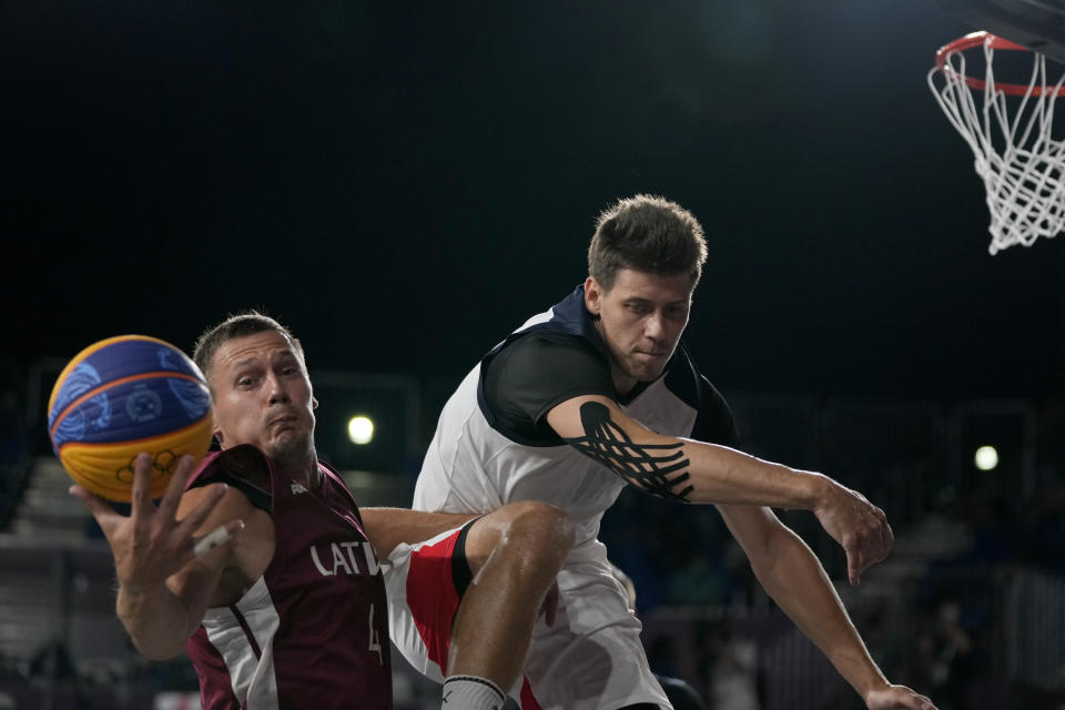 Kirill Pisklov, of the Russian Olympic Committee, right, and Latvia's Agnis Cavars reach for the ball during a men's 3-on-3 gold medal basketball game at the 2020 Summer Olympics, Wednesday, July 28, 2021, in Tokyo, Japan. (AP Photo/Jeff Roberson)