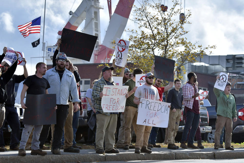 Employees at Bath Iron Works demonstrate against COVID-19 vaccine mandate outside the shipyard on Friday, Oct. 22, 2021, in Bath, Maine. Some American workers are making the painful decision to quit their jobs and abandon cherished careers in defiance of what they consider intrusive mandates requiring all businesses with 100 or more workers require employees to be fully vaccinated or undergo weekly testing. (AP Photo/Josh Reynolds)