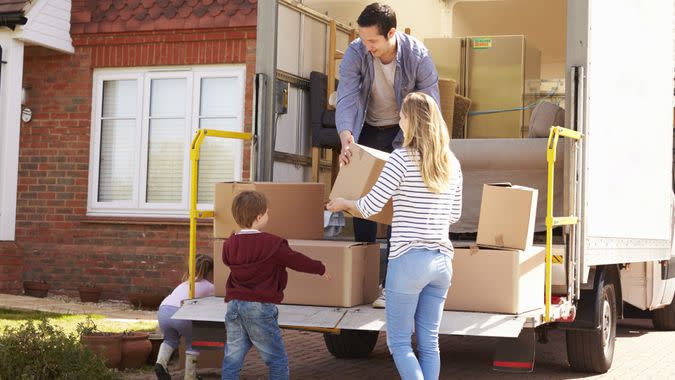 Family Unpacking Moving In Boxes From Removal Truck.