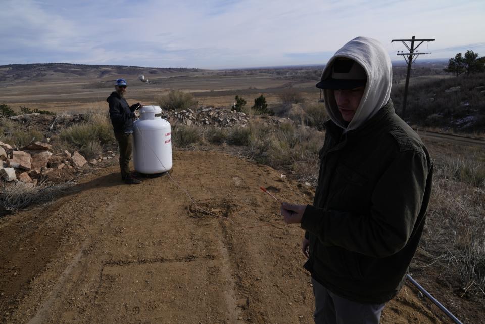 Scott Griebling, water resources engineer at the St. Vrain and Left Hand Water Conservancy District, and Carver Cammans, right, connect a propane tank to cloud seeding equipment on Saturday, Dec. 3, 2022, in Lyons, Colo. The technique to get clouds to produce more snow is being used more as the Rocky Mountain region struggles with a two-decade drought. (AP Photo/Brittany Peterson)