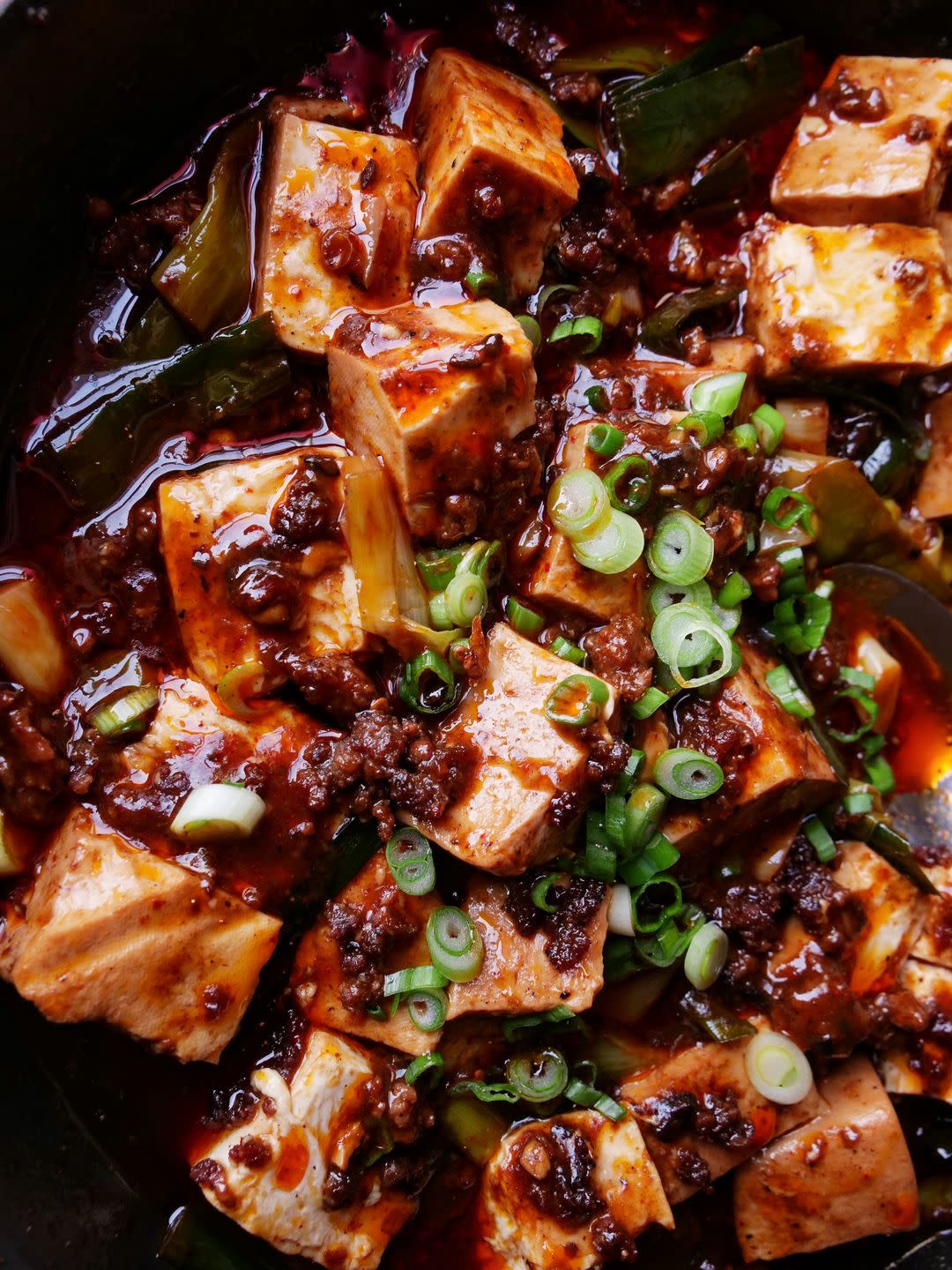 red oil surrounds shiny cubes of flavorful soft tofu sprinkled with sesame and scallions