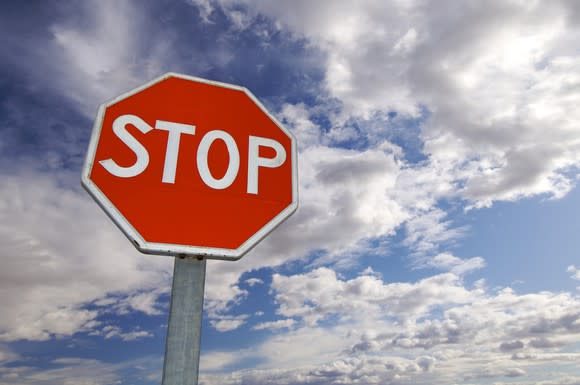 A stop sign surrounded by a partly cloudy sky.