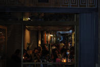 A woman wearing a mask sits with friends at a coffee shop at Ledra street a main shopping street in Nicosia, Cyprus, Tuesday, May 26, 2020. Cyprus took a major step toward a return to normality on Thursday when most restrictions of a two month-long stay-at-home order were lifted, allowing primary school kids to return to classes and hair salons and outdoor cafeterias to re-open. (AP Photo/Petros Karadjias)