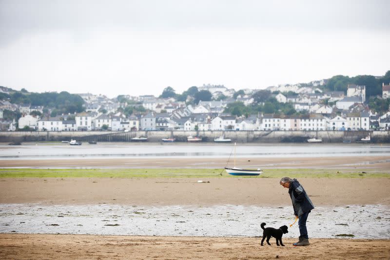 A man walks with his dog on the beach in Instow