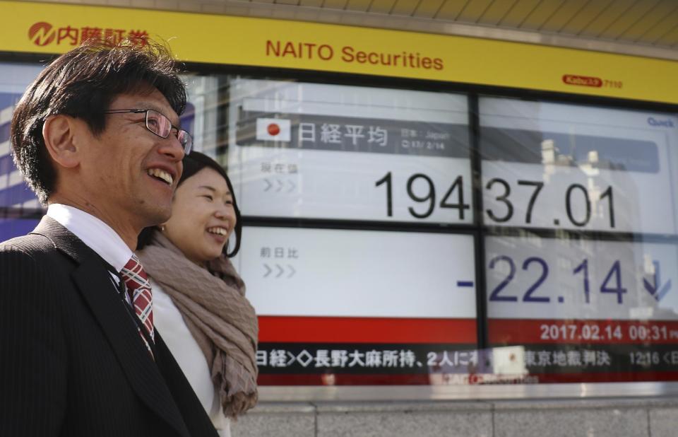 People walk past an electronic stock indicator of a securities firm in Tokyo, Tuesday, Feb. 14, 2017. Shares in Asia fell back after an early rally on Tuesday, as investors awaited comments to Congress by Federal Reserve chair Janet Yellen. (AP Photo/Shizuo Kambayashi)