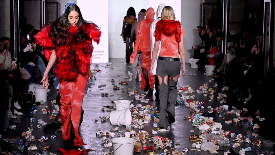 Models walk a trash-strewn runway at the Avavav fashion show, while big screens at either side flashed up excerpts from previous negative show reviews. - Marco M. Mantovani/Getty Images