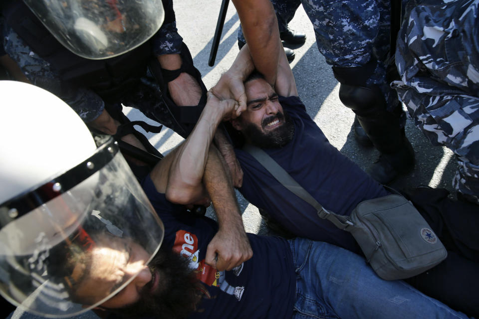 Anti-government protesters lie on a road, as they scream and hold each others while riot police try to remove them and open the road, in Beirut, Lebanon, Thursday, Oct. 31, 2019. Army units and riot police took down barriers and tents set up in the middle of highways and major intersections Thursday. (AP Photo/Bilal Hussein)