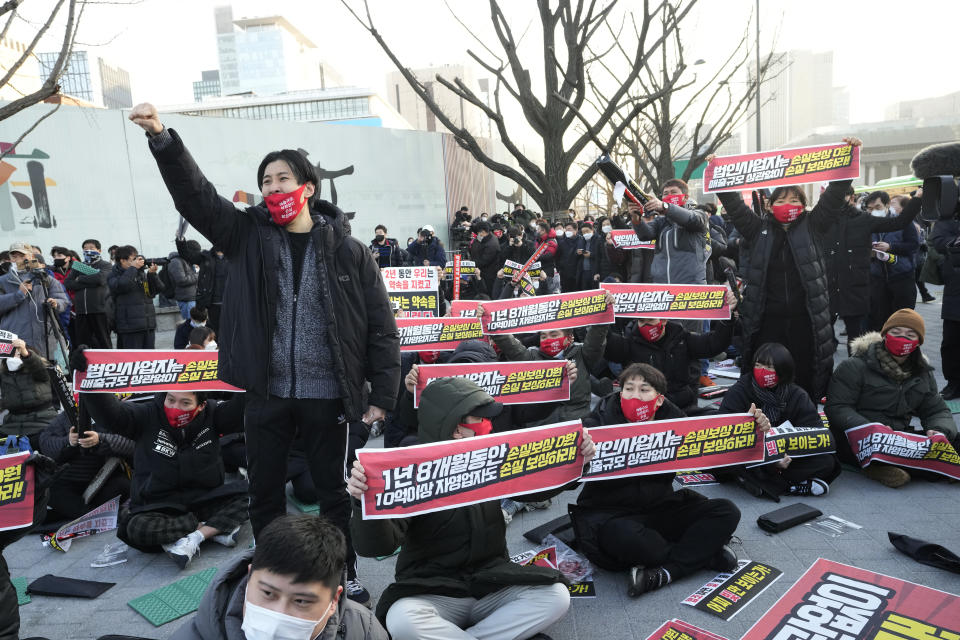 Small business owners stage a rally against the government's social distancing rules near the Government Complex in Seoul, South Korea, Wednesday, Dec. 22, 2021. Hundreds of small business owners rallied on Wednesday, calling for the withdrawal of curfews and other strict COVID-19 restrictions on restaurants, cafes, gyms and other facilities. The signs read "Compensate for loss." (AP Photo/Ahn Young-joon)