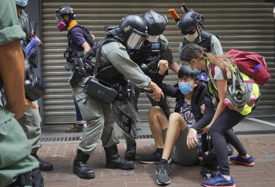 A reporter is helped by police and others after being with sprayed pepper spray in Causeway Bay before the annual handover march in Hong Kong, Wednesday, July. 1, 2020. Hong Kong marked the 23rd anniversary of its handover to China in 1997, and just one day after China enacted a national security law that cracks down on protests in the territory. (AP Photo/Vincent Yu)