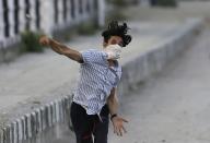 Ein maskierter Demonstrant wirft in Srinagar in Kaschmir einen Stein auf indische Sicherheitskräfte. (Bild: Mukhtar Khan/AP)