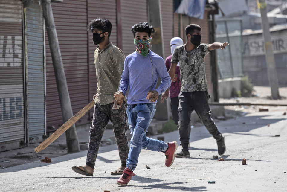 Kashmiri protesters hold stones and sticks as they chase government soldiers while marching on the streets in solidarity with rebels engaged in a gunbattle with soldiers, in Srinagar, Indian controlled Kashmir, Thursday, Sept. 17, 2020. The gunfight erupted shortly after scores of counterinsurgency police and soldiers launched an operation based on a tip about the presence of militants in a Srinagar neighborhood, Pankaj Singh, an Indian paramilitary spokesman, said. (AP Photo/Mukhtar Khan)