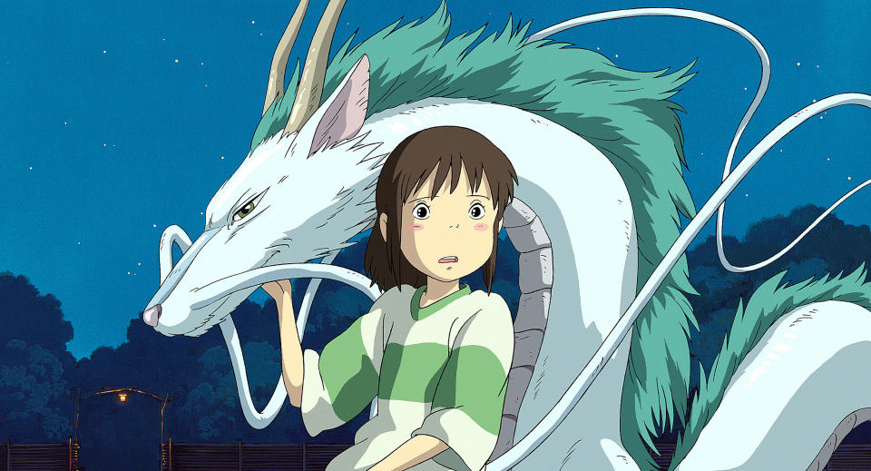 Chihiro from Spirited Away stands beside Haku in dragon form, looking surprised. They are outdoors at night