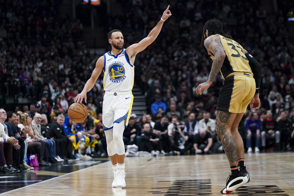 Golden State Warriors guard Stephen Curry (30) motions to teammates while Toronto Raptors guard Gary Trent Jr. (33) defends during the first half of an NBA basketball game Friday, March 1, 2024, in Toronto. (Arlyn McAdorey/The Canadian Press via AP)