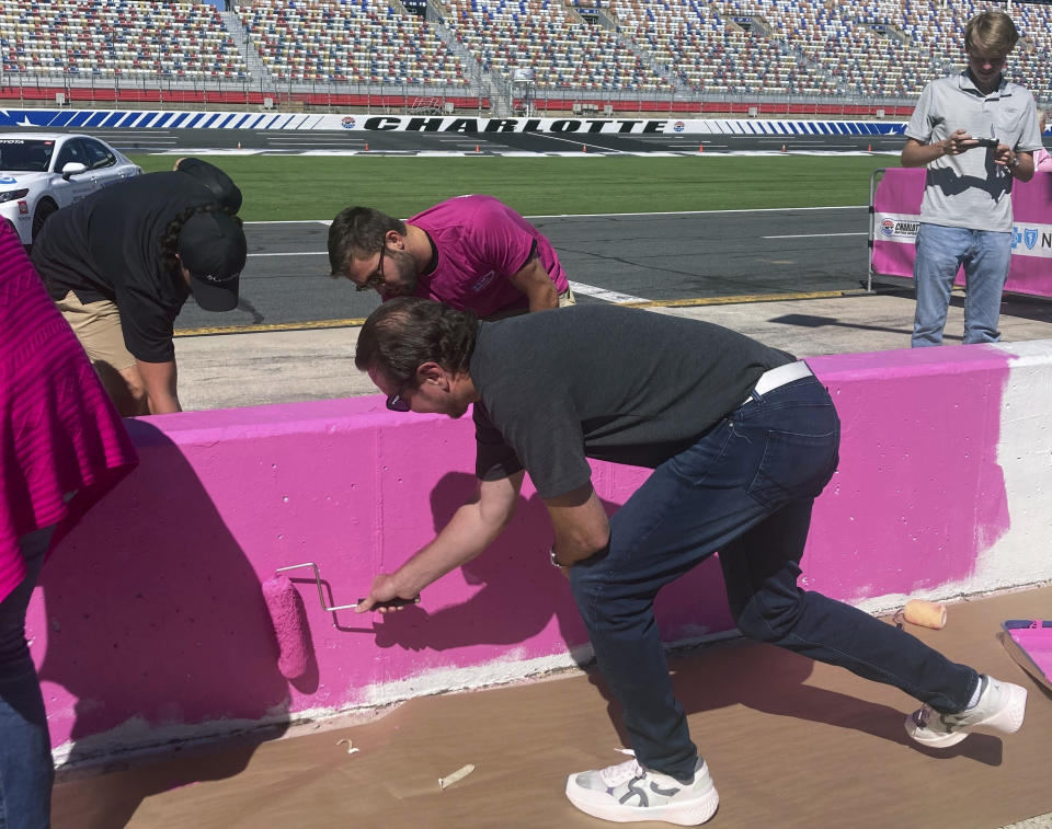 NASCAR driver Kurt Busch, foreground, helps paint the pit wall pink during 10th annual recognition of Breast Cancer Awareness Month at Charlotte Motor Speedway in Concord, N.C., Tuesday, Sept. 27, 2022. (AP Photo/Jenna Fryer)