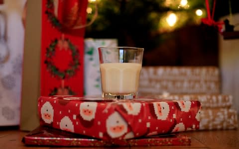 A glass of milk resting on presents underneath a Christmas tree - Credit: Jonathan Brady/PA