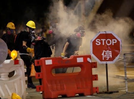An anti-extradition bill protester uses a slingshot toward police officers which fired tear gas during a protest in Hong Kong