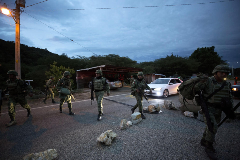 Soldiers wearing the armbands of Mexico's National Guard walk at a migration checkpoint on the highway north of Comitan, Chiapas State, Mexico, Saturday, June 15, 2019. Under pressure from the U.S. to slow the flow of migrants north, Mexico plans to deploy thousands of National Guard troops by Tuesday to its southern border region.(AP Photo/Rebecca Blackwell)