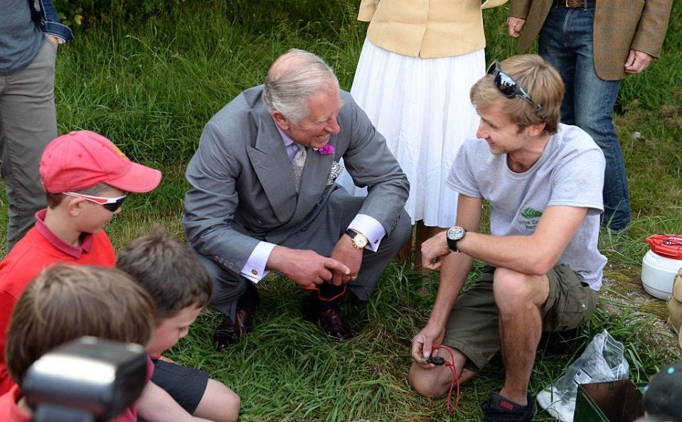 Prince Charles kneels down with kids on the ground