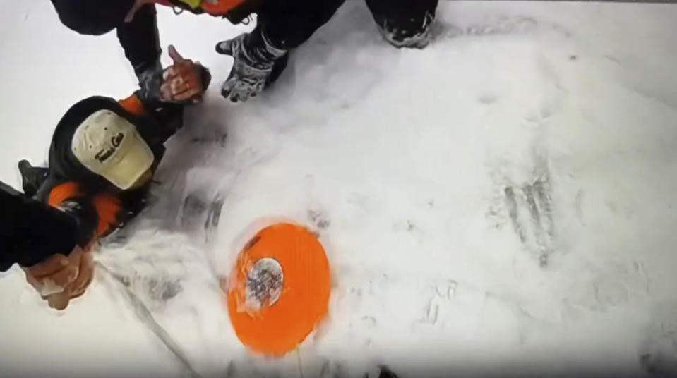 In this image taken from video provided by Michigan State Police, officers work to extricate a man from the waters of frozen Arbutus Lake in Grand Traverse County, Mich., Thursday, Jan. 18, 2024. The man was rescued after a quick-thinking state police officer used the stranded man's dog to get rescue equipment to him and pull the man to safety in a rescue captured on video. (Michigan State Police via AP)