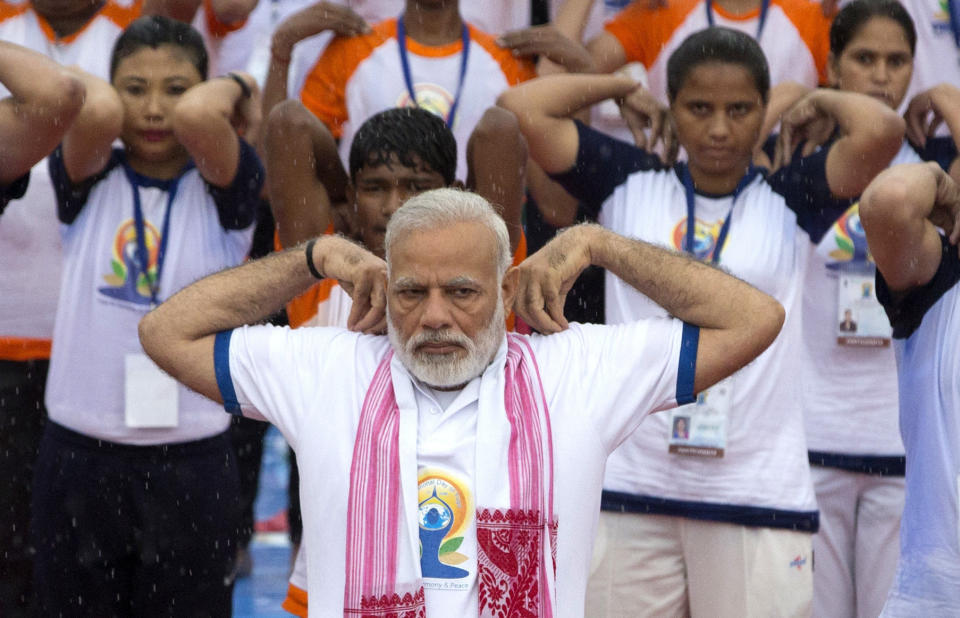 FILE- In this June 21, 2017 file photo, Indian Prime Minister Narendra Modi, center, performs yoga with thousands of Indians to mark international yoga day in Lucknow, India. Modi’s Hinduism often goes unspoken, but it is regularly on display. While things like yoga and vegetarianism have little religious connotation in the West, their Hindu connections are clear to Indian voters _ especially when practiced by a politician. (AP Photo/Rajesh Kumar Singh, File)