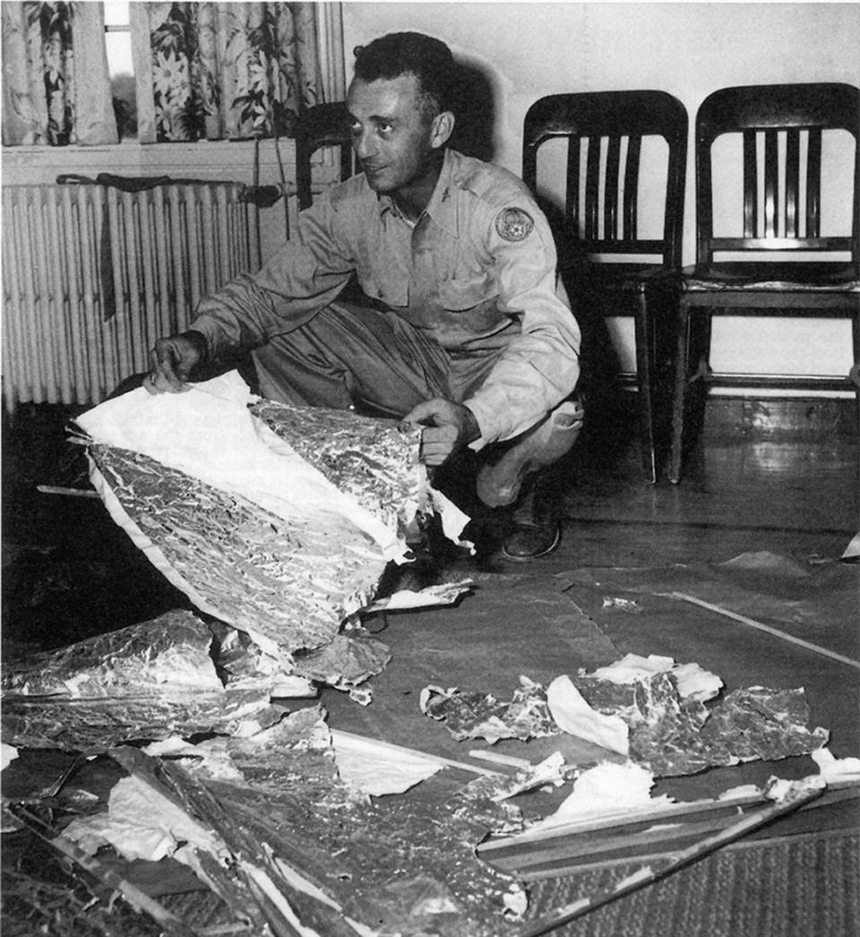 An intelligence officer holds some of the debris from the “flying disc” in 1947.