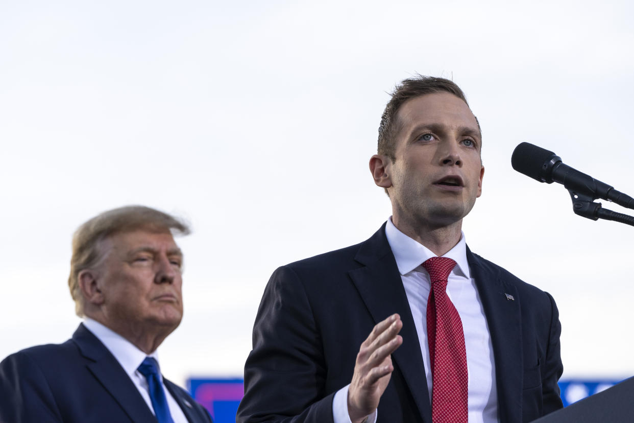 Former President Donald Trump listens as Max Miller, in suit and tie, takes the microphone.