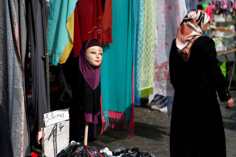 FILE PHOTO: A woman walks past a mannequin wearing an hijab headscarf at a market in the Brussels district of Molenbeek