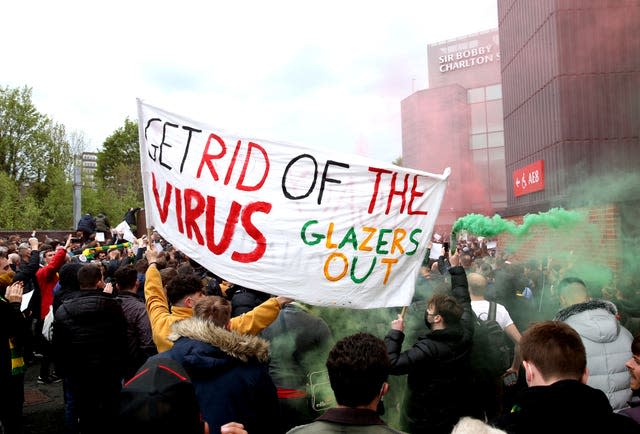 Fans holds up a banner as they protest against the Glazer family