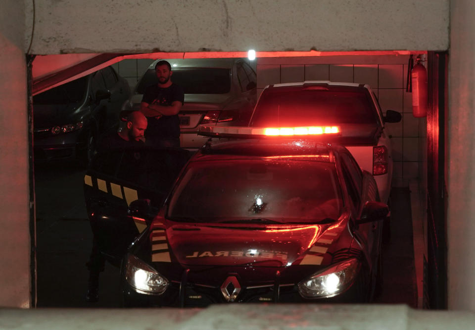 Federal police officers stand in a residential building garage in Rio de Janeiro, Brazil, Tuesday, Nov. 19, 2019. Brazilian police are seeking the arrest of several people, including Paraguay's ex-President Horacio Cartes , as part of a massive investigation into kickbacks and money laundering. (AP Photo/Silvia Izquierdo)