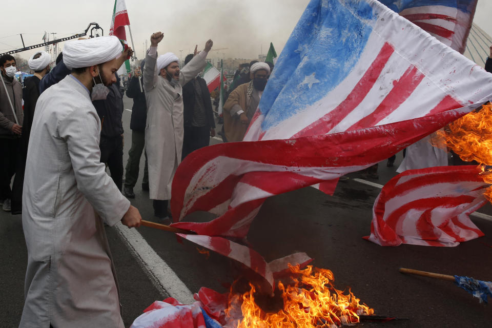 Clerics burn representations of the U.S. flag during the annual rally commemorating the anniversary of Iran's 1979 Islamic Revolution in Azadi (freedom) Square in Tehran, Iran, Friday, Feb. 11, 2022. Thousands of cars and motorbikes paraded in the celebration, although fewer pedestrians were out for a second straight year due to concerns over the coronavirus pandemic. (AP Photo/Vahid Salemi)