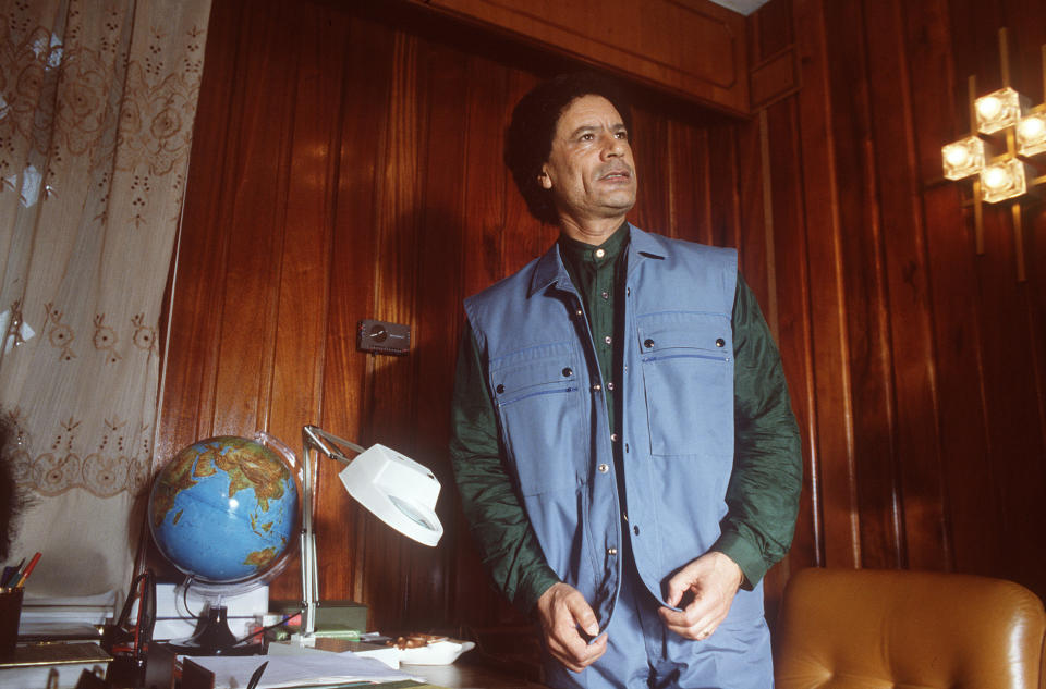 The utilitarian body warmer with matching trousers, offset by a emerald green shirt, is a look few can pull off. His philosophical stance and nearby globe save him from looking as though he had come to fix the pipes.    Gaddafi addresses journalists in 1986 in Tripoli, during a meeting of "The High Command of The Revolutionary Forces of The Arab Nation". 