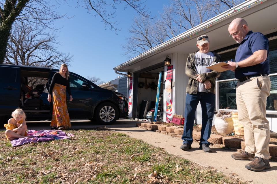 Earl McIntosh, right, helps Topeka resident Donald Williams Jr. fill out a voter registration form and petition regarding property taxes Friday afternoon, while Ashley Hail and her 4-year-old daughter Blakely look on.