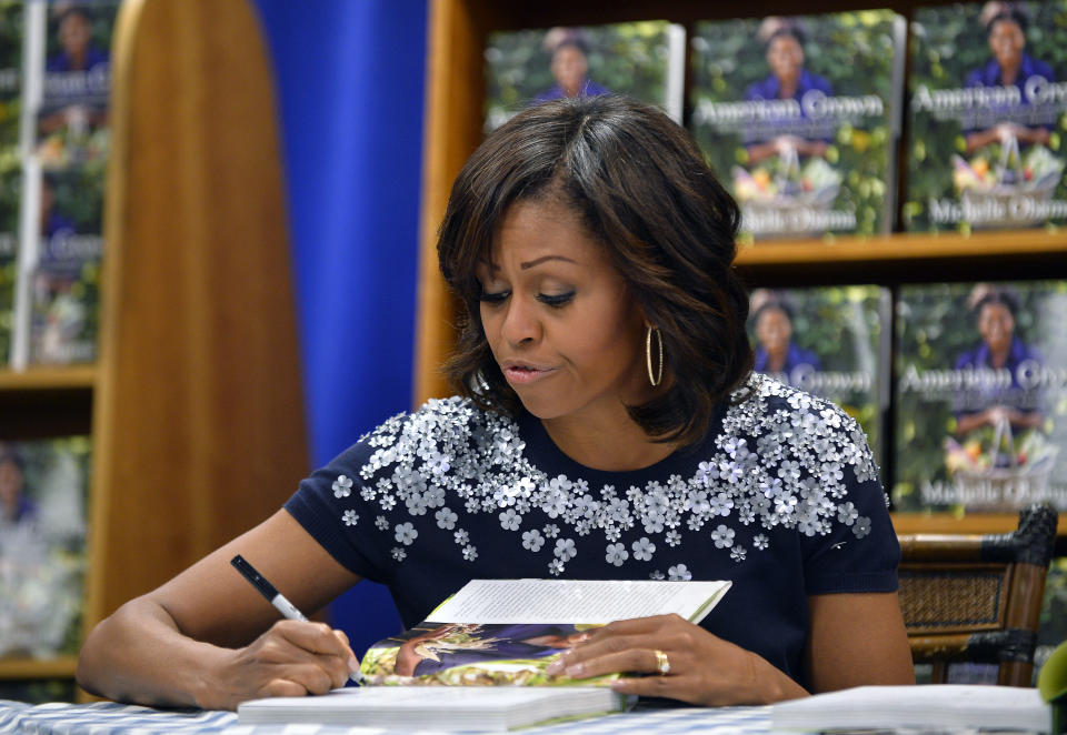 US First Lady Michelle Obama signs a copy of her book 'American Grown: The Story of the White House Kitchen Garden and Gardens Across America,' during a book signing event at Politics & Prose in Washington, DC, on May 7, 2013. Photo credit:  JEWEL SAMAD/AFP/Getty Images