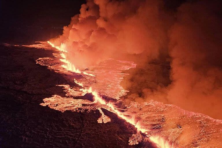 En esta imagen distribuida por el Departamento de Protección Civil y Gestión de Emergencias de Islandia se ve humo y lava fluyendo y tiñendo el cielo de naranja durante una erupción volcánica en la península de Reykjanes, 3 km al norte de Grindavik, al oeste de Islandia, el 19 de diciembre de 2023.